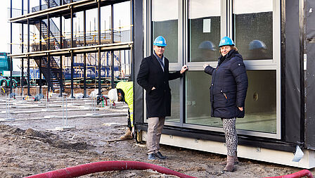 Wethouder Carlieke van Staalduinen (rechts) en Reinder Zuurmond, manager vastgoed bij Arcade, bij het plaatsen van de eerste tijdelijke woning op Flora Campus Westland.