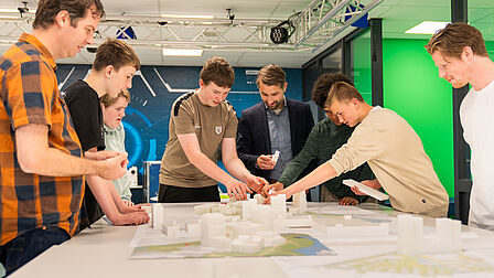  Adviseur fysieke leefomgeving Gerard van Gaalen met Sjoerd Timmerman, locatiedirecteur en leerlingen rond maquette.
